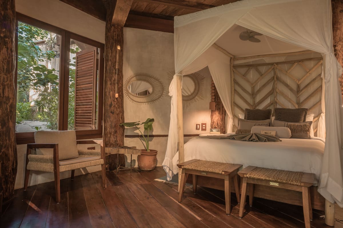 A bedroom with a canopy bed, wooden furniture, and a view of the outdoors.