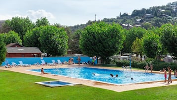 Una piscina al aire libre de temporada, sombrillas, tumbonas