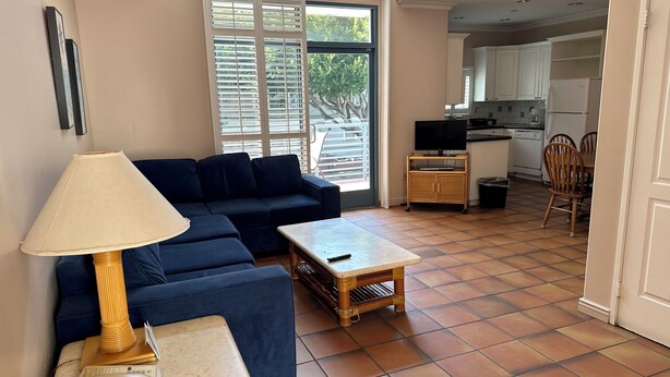 A living room with a sofa, a small table, a lamp, and a telephone. There is a kitchen area visible through an open door. - Sea Shore Motel (Santa Monica)