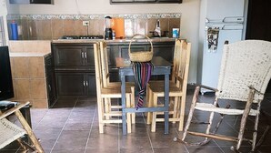 A kitchen with dark cabinets, a tiled floor, and a dining area with wooden chairs and a table. - El Huastequito (Ciudad Valles)