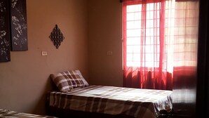 A room with two beds, a ceiling fan, an air conditioning unit, and a window with red curtains. - El Huastequito (Ciudad Valles)