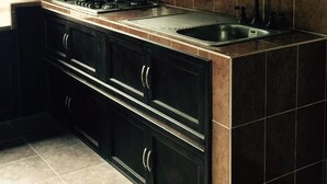 A kitchen with dark cabinets, a gas stove, and a sink. - El Huastequito (Ciudad Valles)