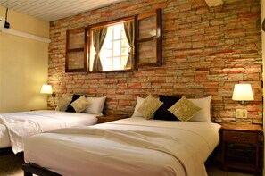 A hotel room with two beds, a brick wall, and a window with curtains. - Hostal Isabella (Cienfuegos)