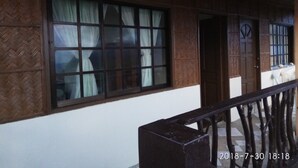 Un bâtiment doté d’une grande fenêtre, d’une porte en bois et d’une balustrade.