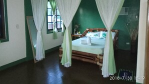 Une pièce avec un lit, des rideaux, une fenêtre et un mur vert.