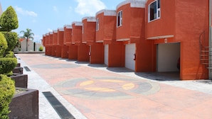 A row of orange buildings with a patterned walkway and a circular design in the center. - Motel Séptimo Eclipse - Adults Only (Acolman)