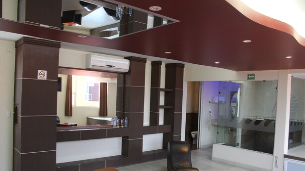 A hotel lobby with a reception desk, a seating area, and a glass-enclosed shower area. - Motel Séptimo Eclipse - Adults Only (Acolman)