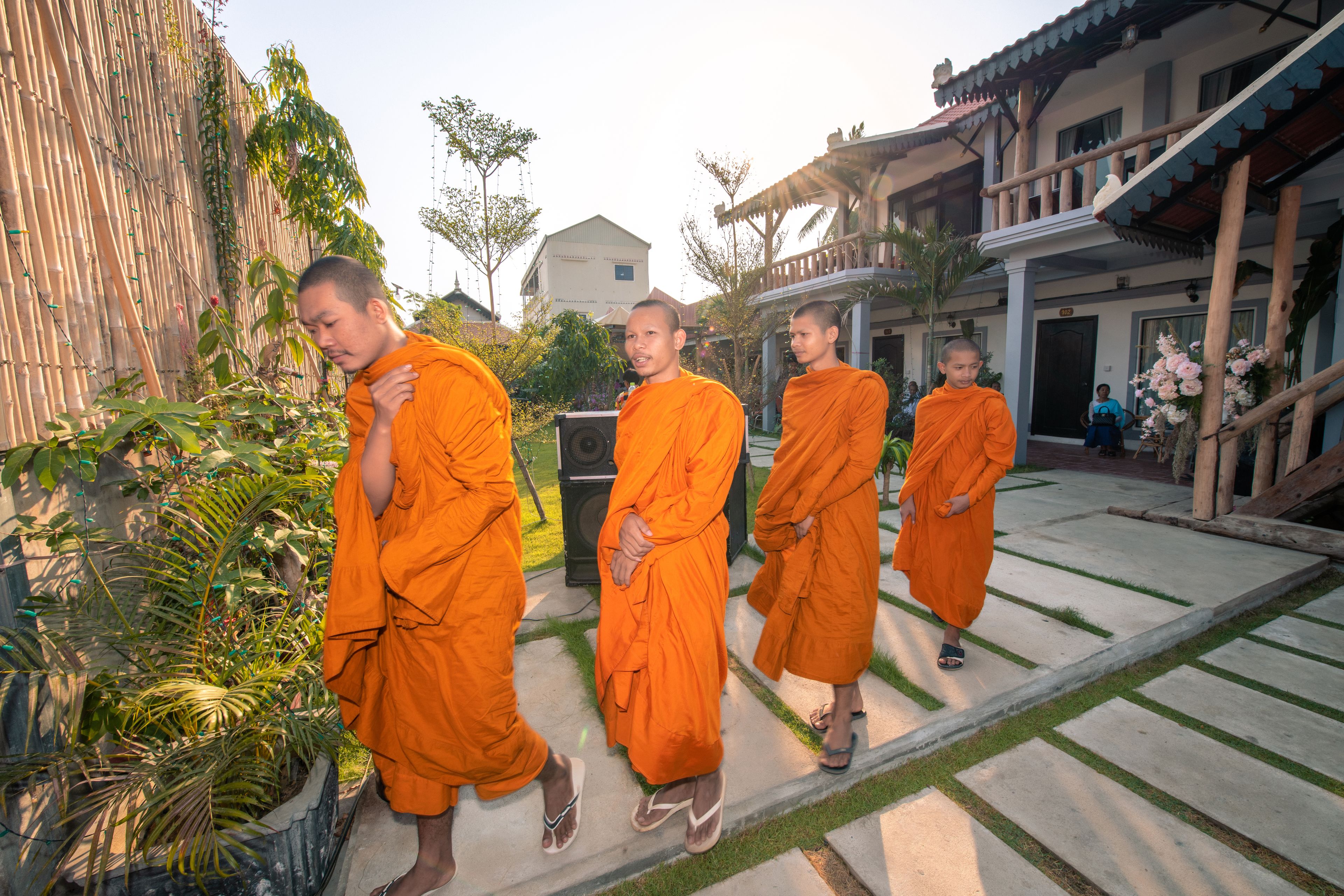 Monks in orange robes walking on a stone pathway.
