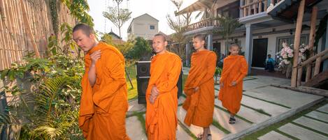 Monks in orange robes walking on a stone pathway.
