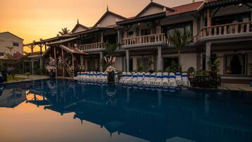 A hotel with a swimming pool, traditional architecture, and balconies.