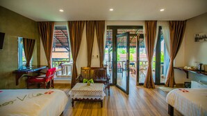 Habitación de hotel con dos camas, un escritorio y una silla. Tiene un balcón con vistas al exterior.