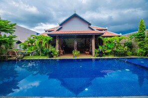 Une maison traditionnelle thaïlandaise avec une piscine située devant.