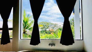 Un baño con bañera, una ventana con cortinas y vistas al exterior.