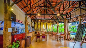 Un espacio interior amplio con suelo de madera, mesas, sillas y una zona de bar.