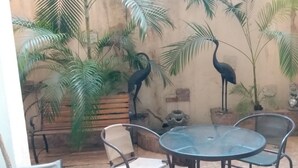 A patio area with a round table and chairs, surrounded by potted plants and a wall with a rustic appearance. - Hotel Casa Aluge (Santo Domingo)