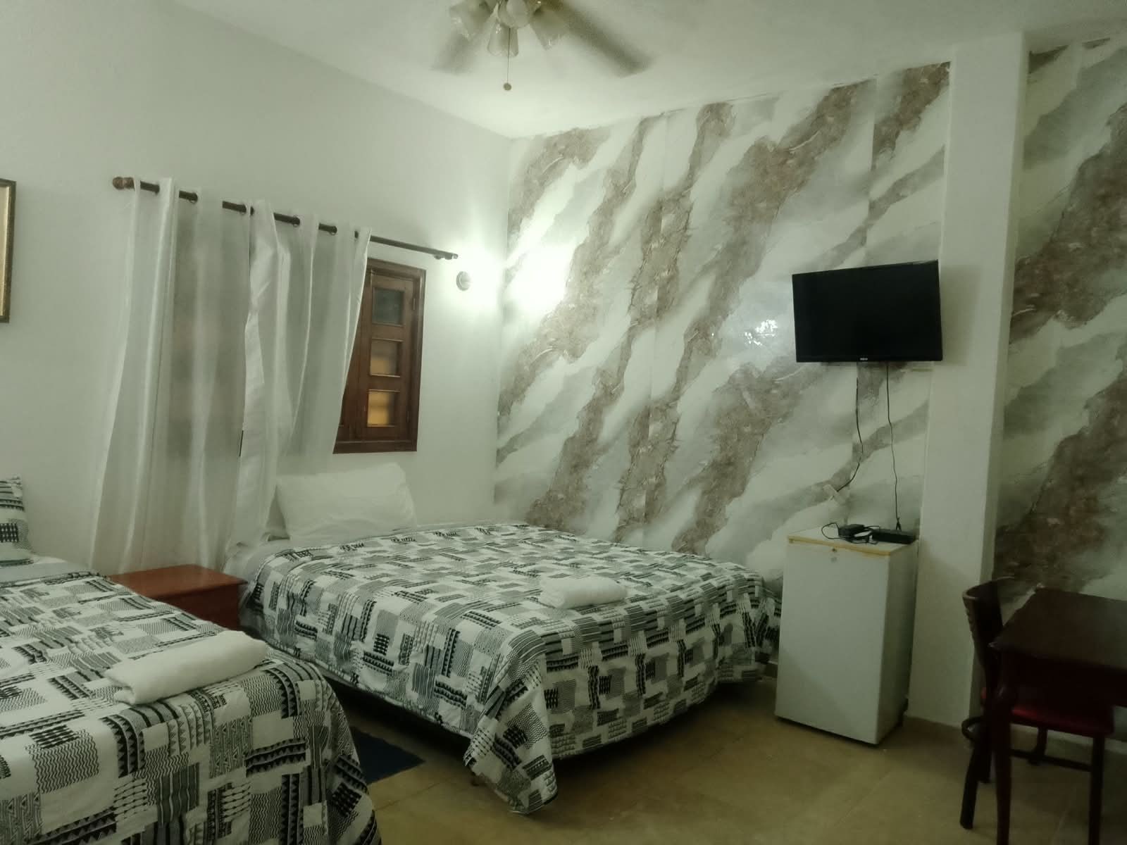 A bedroom with two beds, a TV, and a desk.