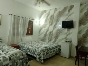 Une chambre avec deux lits, une télévision et un bureau.