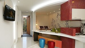 Un intérieur moderne comprenant un espace cuisine, un coin repas et un salon avec un téléviseur fixé au mur.