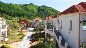 Un quartier résidentiel caractérisé par des bâtiments blancs, des toits recouverts de tuiles rouges et un sentier qui traverse la verdure.