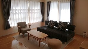 Una sala de estar con sofá, sillón, mesa de centro, reposapiés y alfombra.
