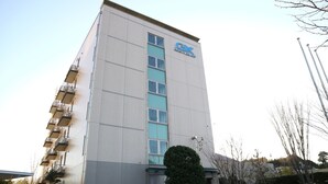 A tall, modern building with a prominent logo on the side. It features multiple floors with balconies and large windows. - KEIKYU EX INN Yokosuka Research Park (Yokosuka)