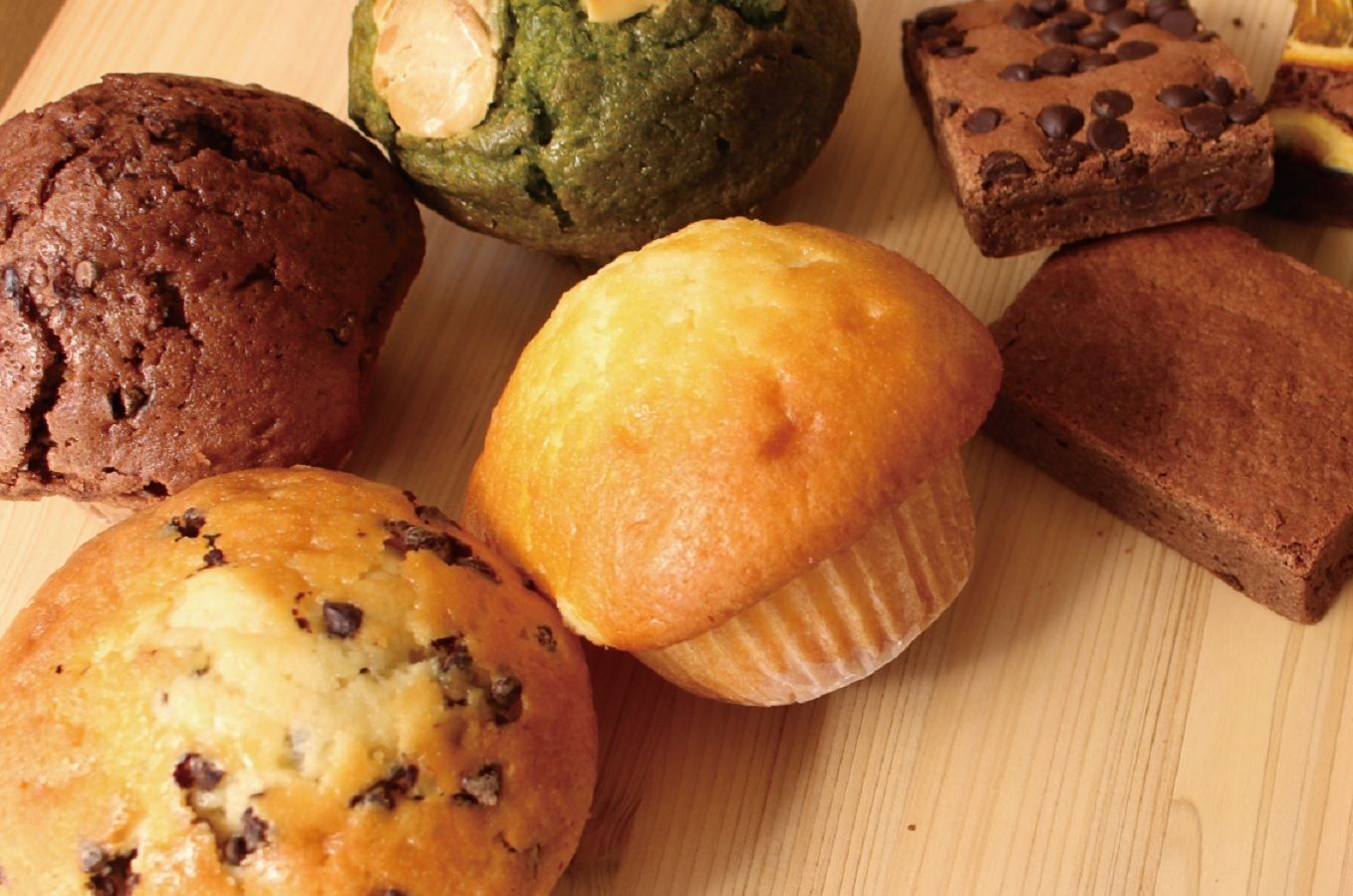 A variety of baked goods including muffins and cookies on a wooden surface.