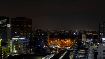 Un paisaje urbano nocturno con edificios iluminados y una calle concurrida.