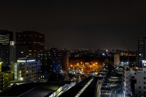Un paisaje urbano nocturno con edificios iluminados y una calle concurrida.