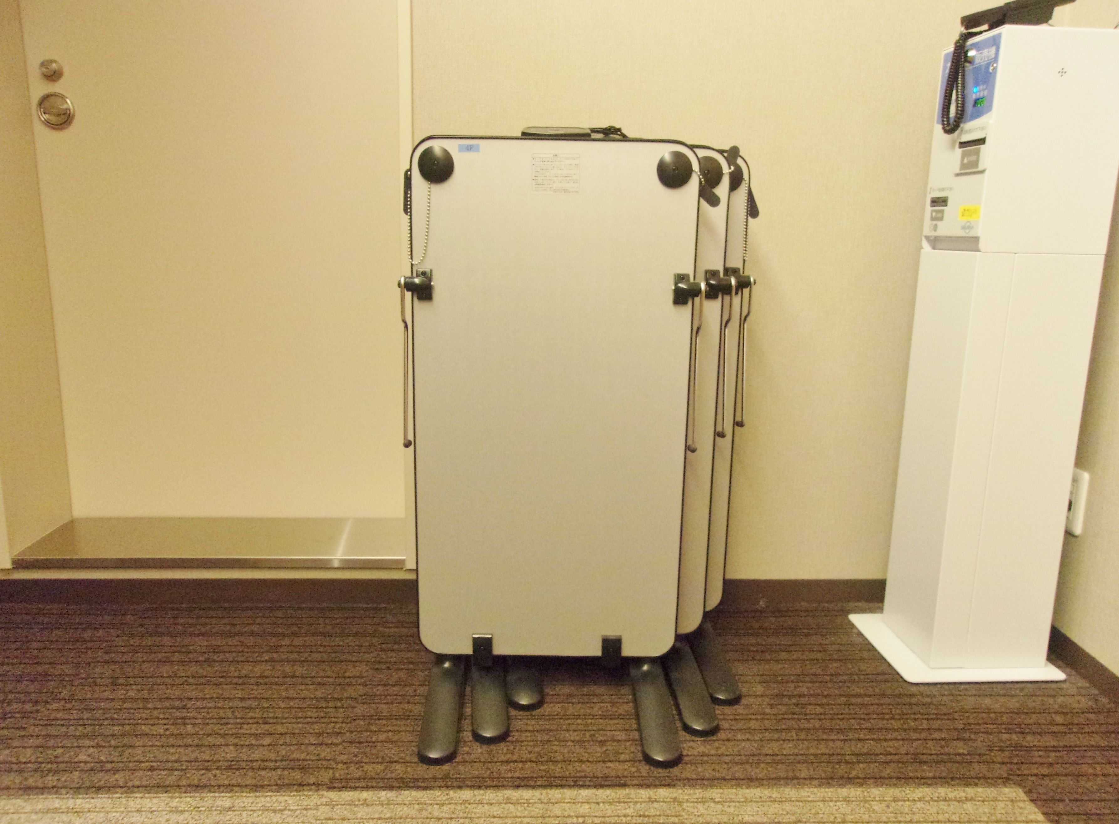 A room with a white door, a white wall, and a white refrigerator.