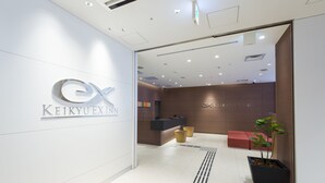 Ett modernt entréområde med en logotyp, en receptionsdisk, sittplatser och en krukväxt.