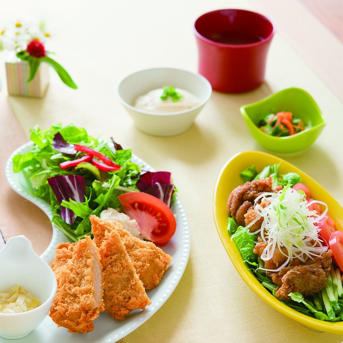 Un repas composé de différents plats, notamment une salade, du poulet pané et une soupe.