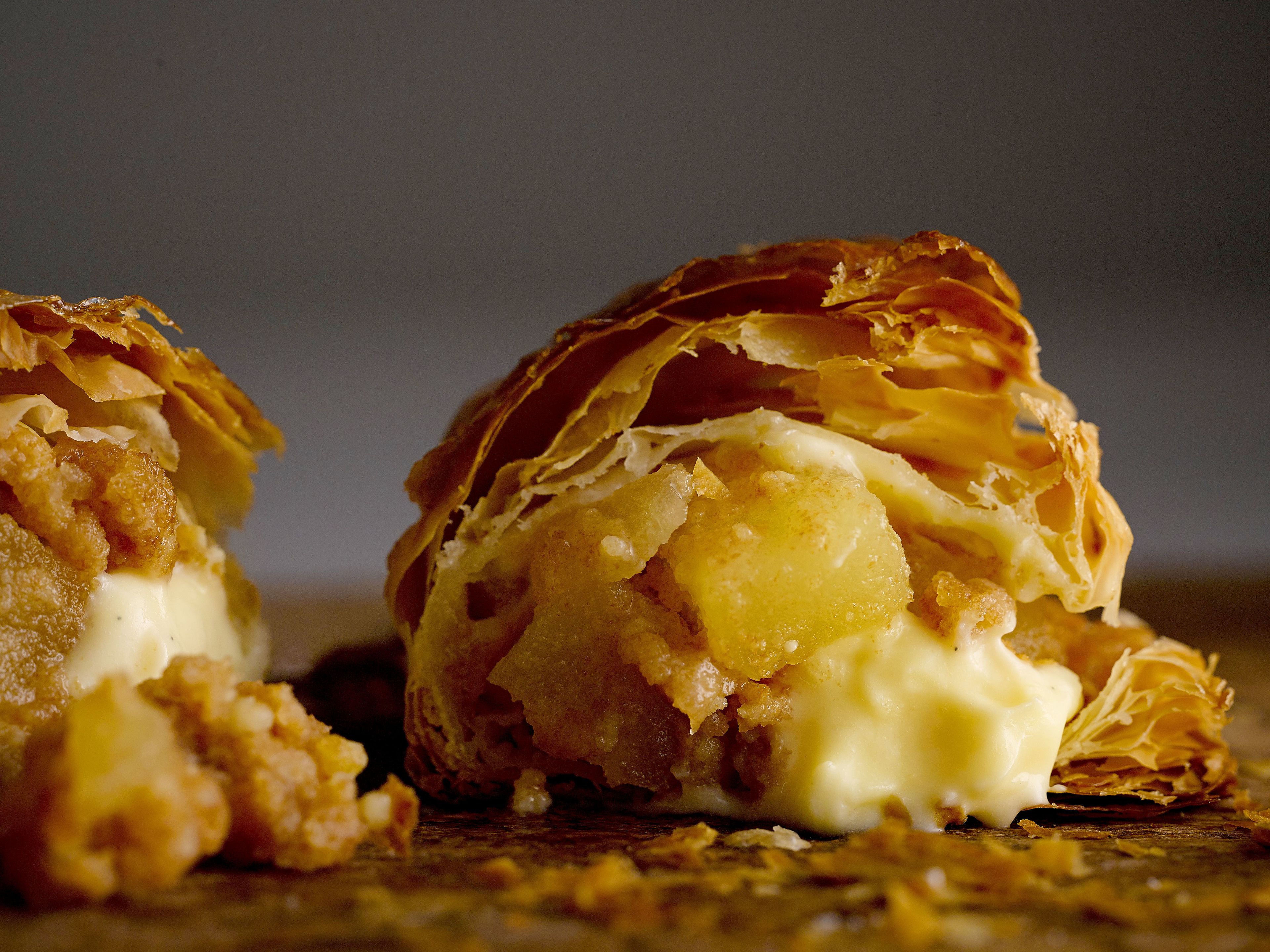 A close-up of a pastry with flaky layers and a creamy filling.
