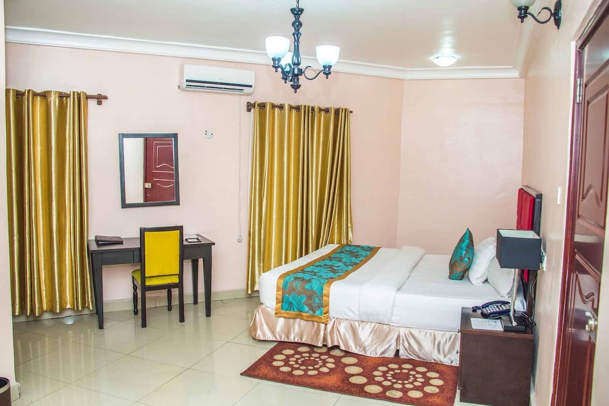 Habitación de hotel con cama, escritorio, silla, lámpara de escritorio, teléfono y aire acondicionado de pared.