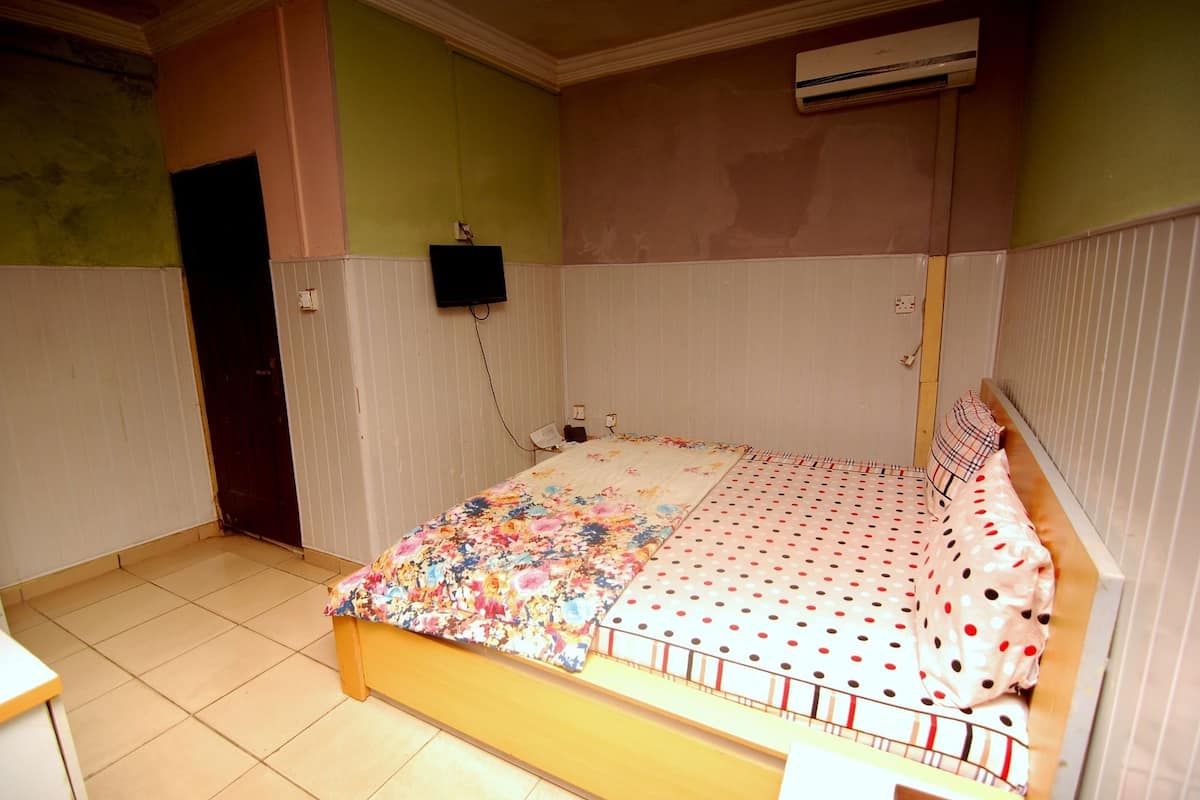Een slaapkamer met een bed, een wandairconditioner en een deur.