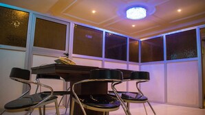 A room with a piano, four chairs, and large windows. - Taverna Guest House (Lagos)