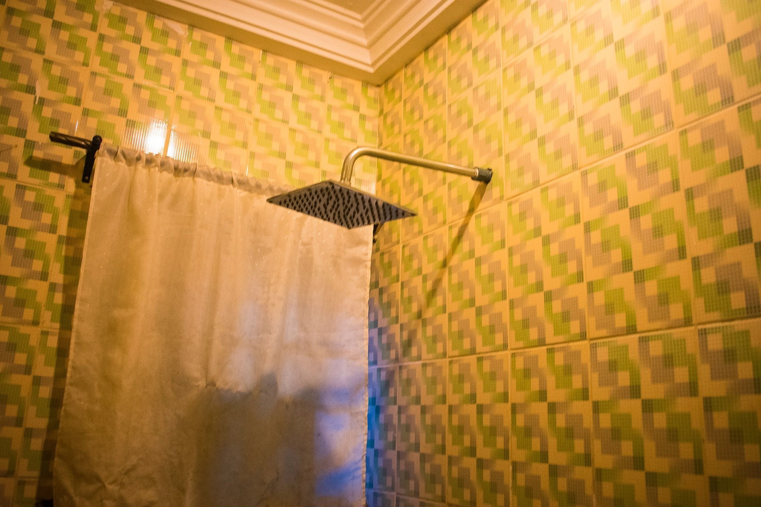 A bathroom with a shower, tiled walls, and a curtain.