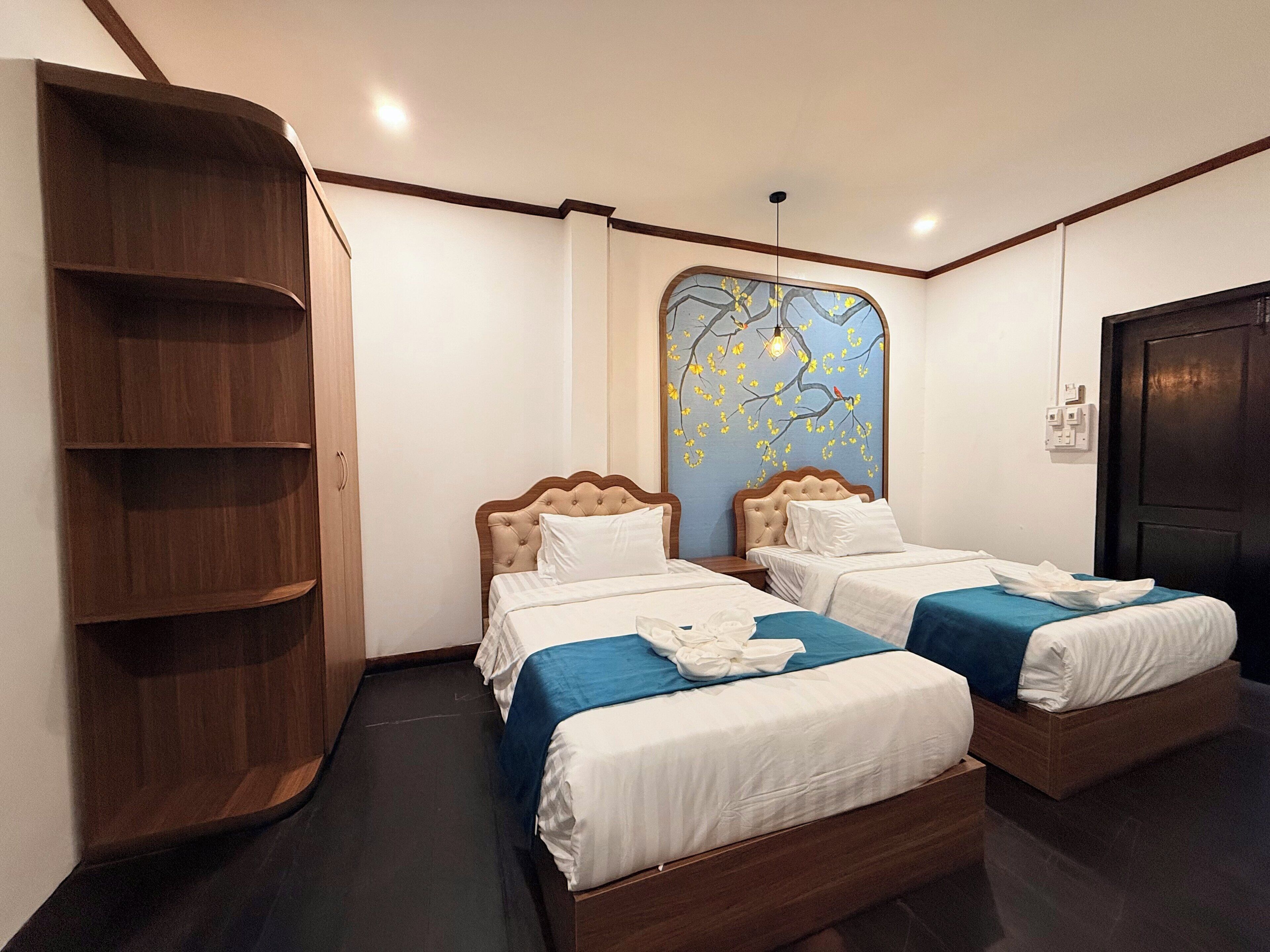 Habitación de hotel con dos camas, un armario y un adorno en la pared.