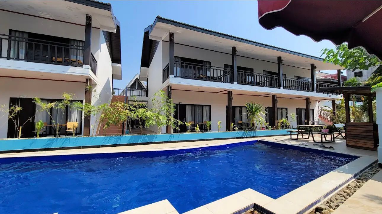 A modern hotel with a swimming pool, balconies, and outdoor seating areas.