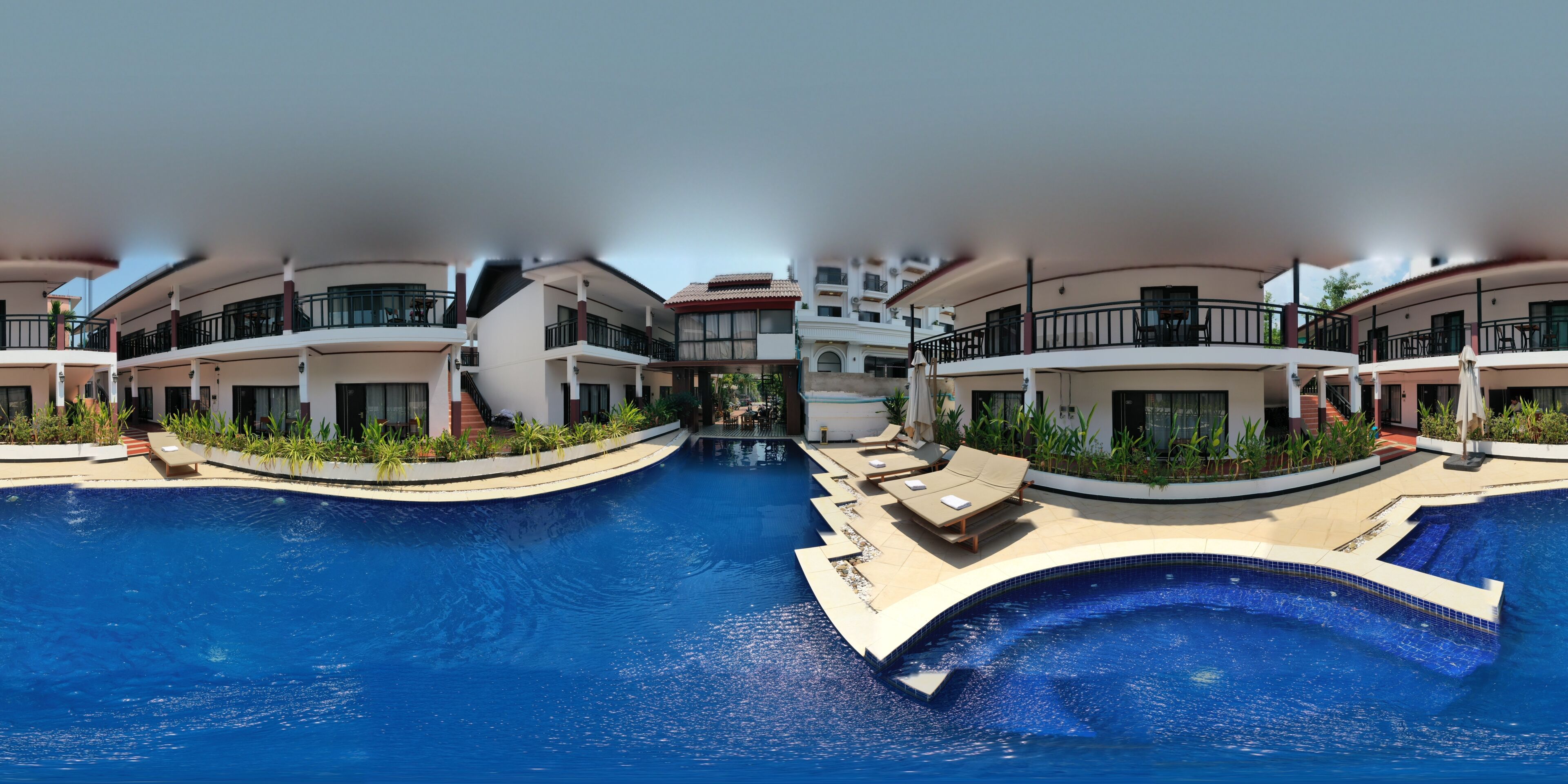 A modern hotel with a swimming pool, multiple balconies, and outdoor seating areas.