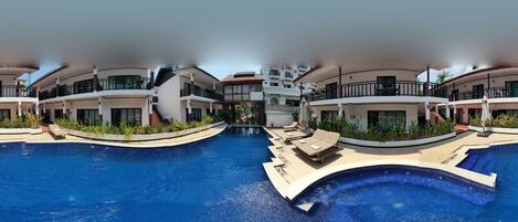 A modern hotel with a swimming pool, multiple balconies, and outdoor seating areas.
