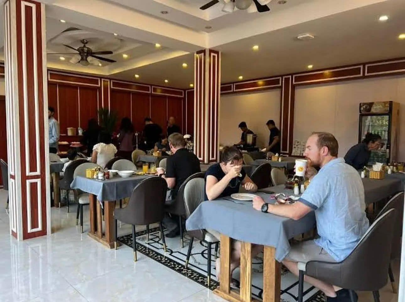 Een restaurant met tafels, stoelen en etende gasten.
