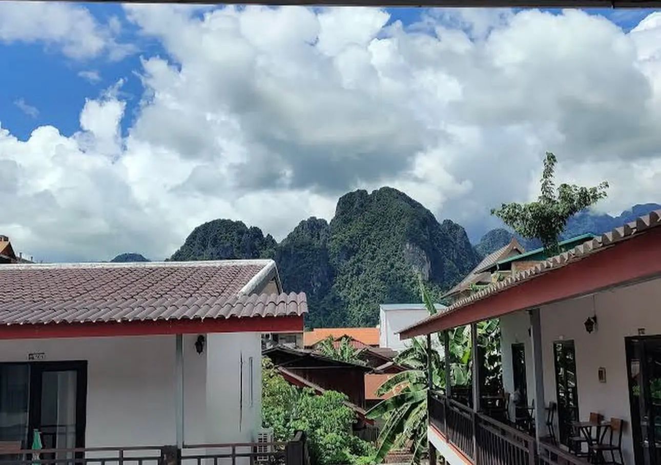 A building with a red roof, a balcony, and a view of mountains.