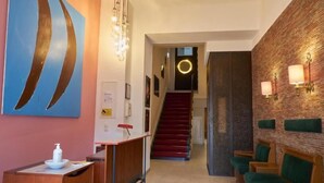 Eine Hotellobby mit Empfangstresen, einer Treppe und einer Sitzecke.