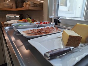 A buffet setup with various food items including cheese, ham, and fruits.