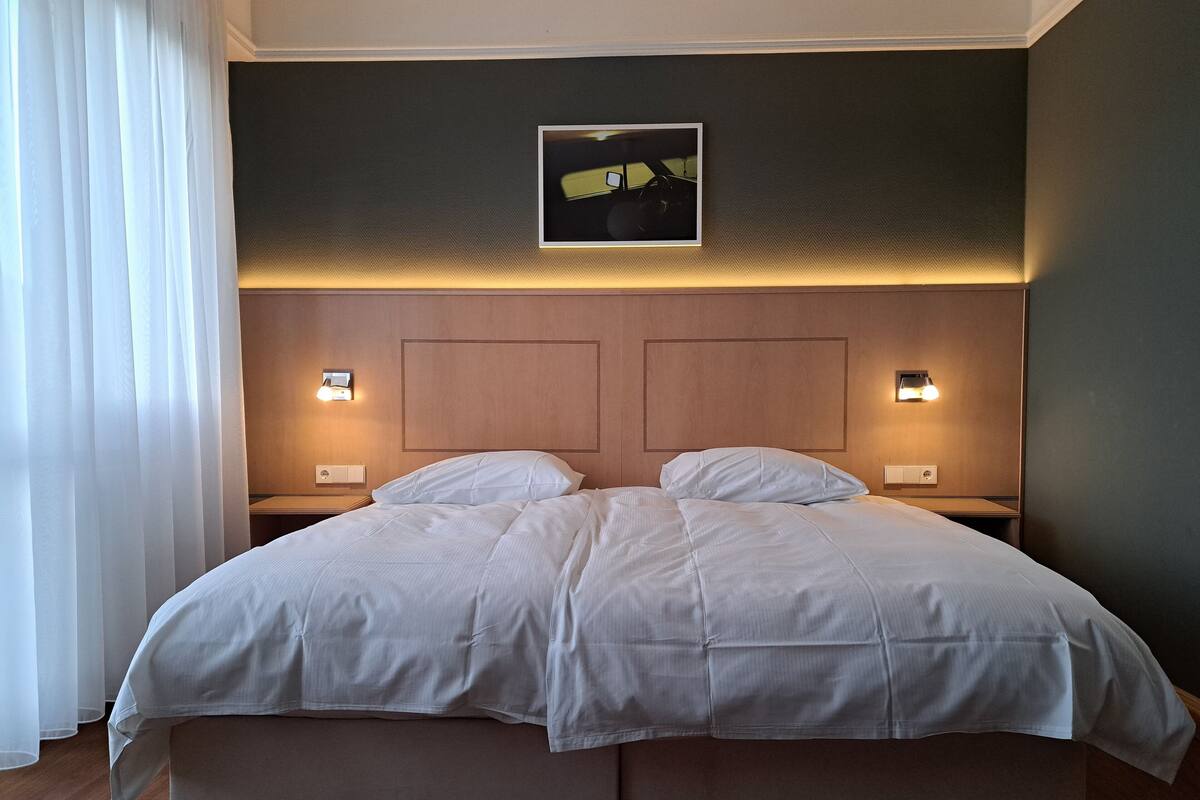 A double bed with a wooden headboard, two bedside tables with lamps, and a framed picture above the headboard.