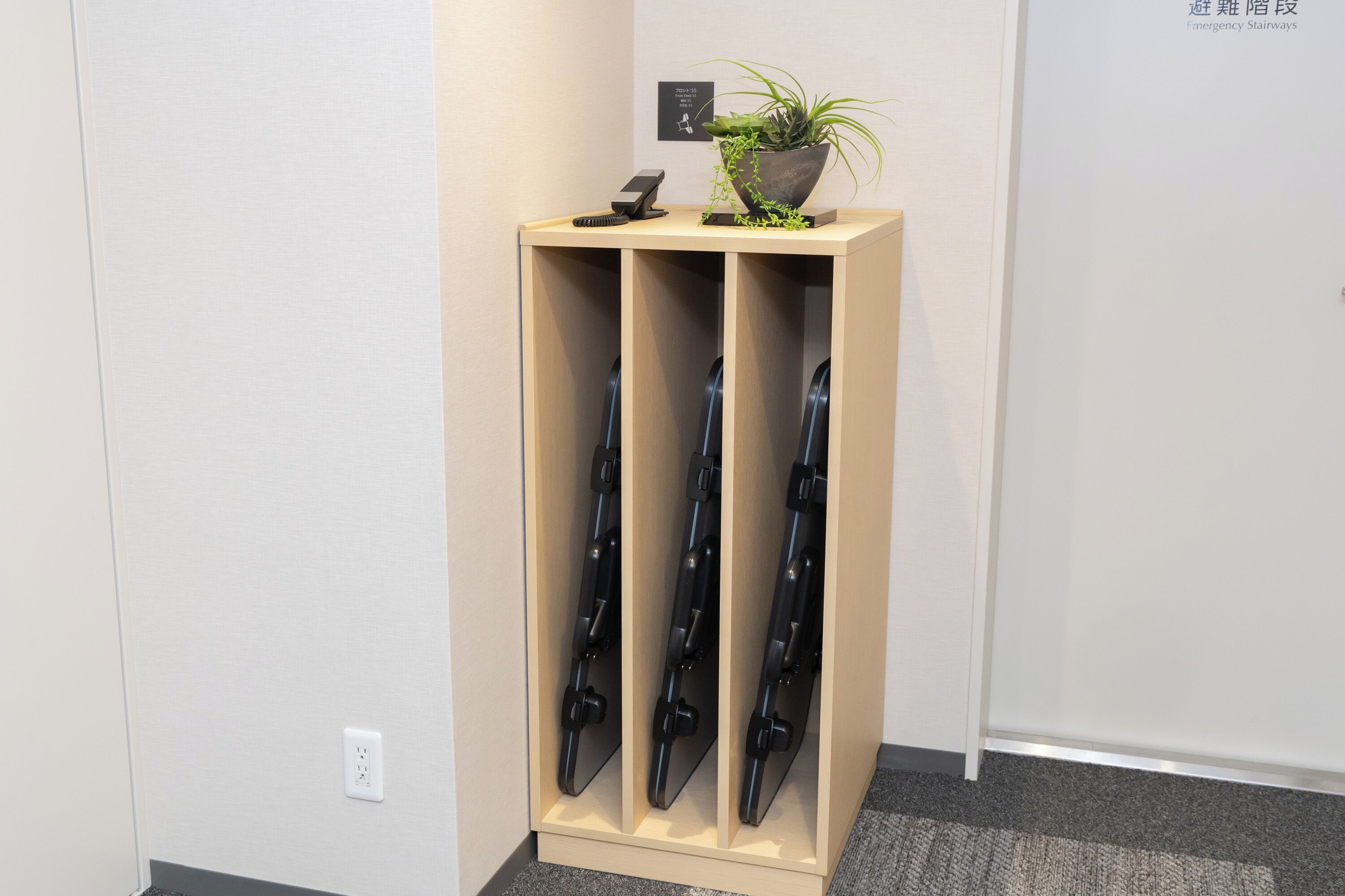 A wooden display stand with a potted plant and a small electronic device on top.