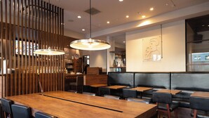 A restaurant interior with a wooden dining table, black upholstered booths, and pendant lighting. - Keikyu Ex Inn Yokohama Station East (Yokohama)