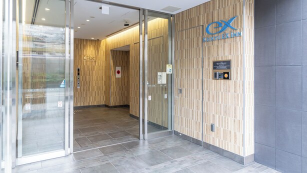 A modern hotel lobby with a wooden wall and a glass entrance. - Keikyu Ex Inn Yokohama Station East (Yokohama)