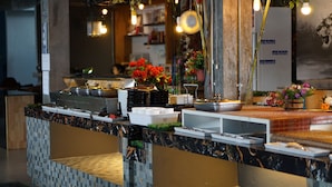 A hotel reception area with a marble counter, a fan, and various amenities including a coffee station and flower arrangements. - Nine Blue Residence (Pattaya)