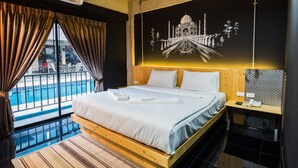 A hotel room with a large bed, a view of a swimming pool, and a wall-mounted air conditioner. - Nine Blue Residence (Pattaya)